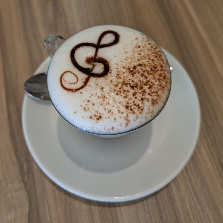 A small espresso macchiato topped with a spoonful of silky milk foam in a white cup