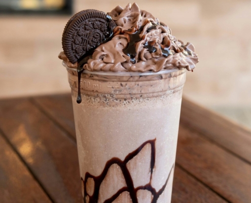 A chocolate chip frappe topped with whipped cream in a clear glass