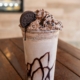A chocolate chip frappe topped with whipped cream in a clear glass