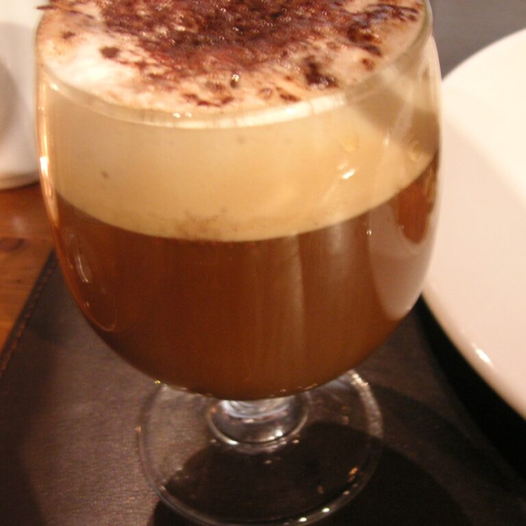 Realistic coffee punch drink in a stemmed glass with creamy foam and cocoa dusting